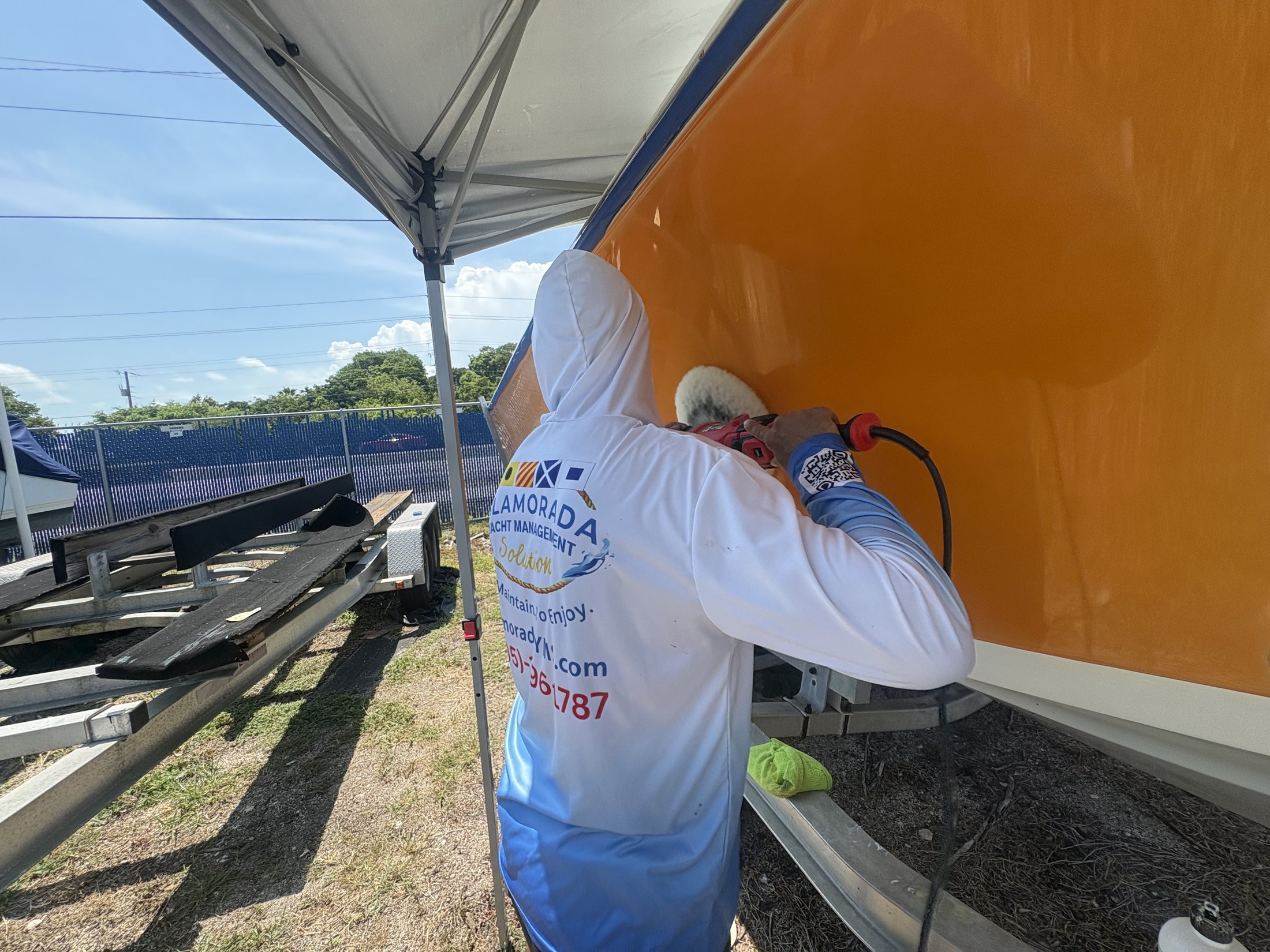 Technician polishing an orange gelcoat hull