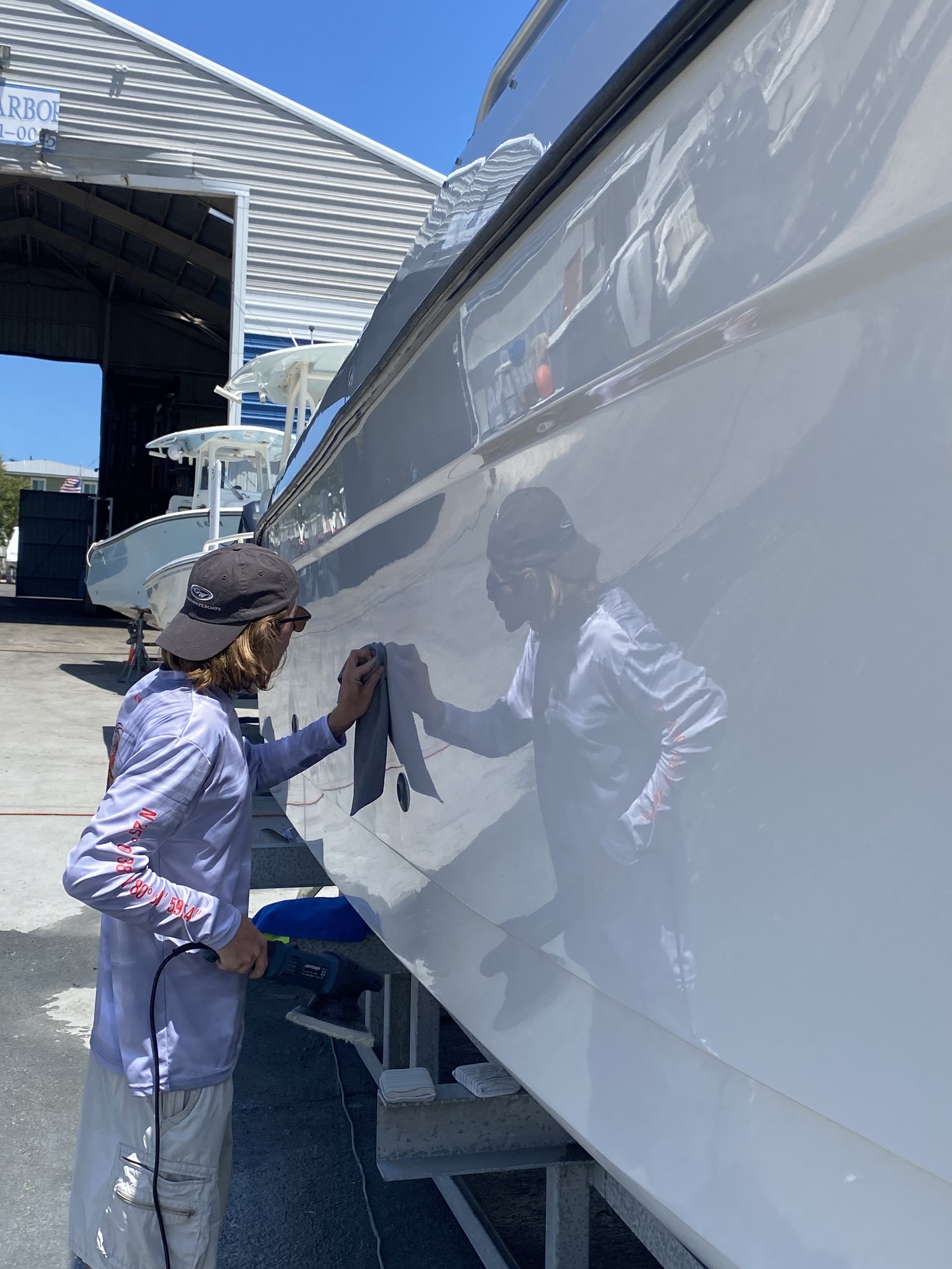 Technician machine polishing a yacht hull