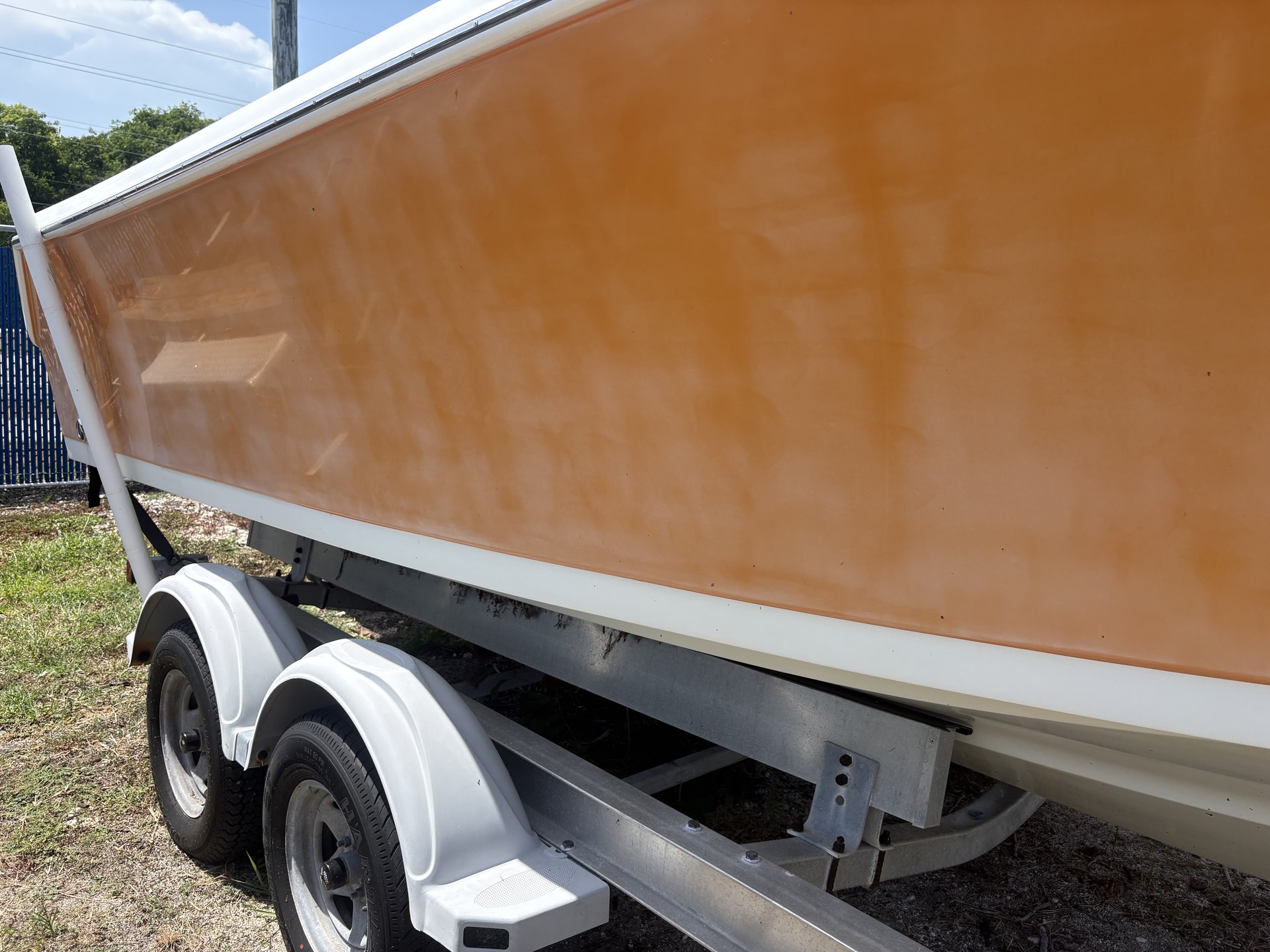 Before gelcoat correction: orange center-console hull with visible oxidation and uneven gloss